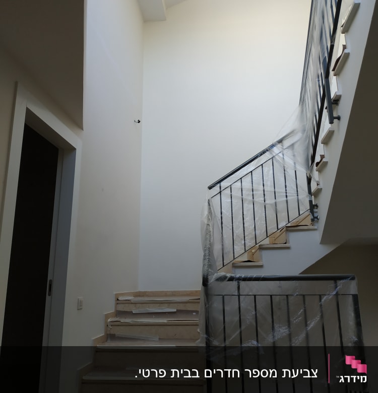 מדרגות עם מעקה מכוסה בניילון להגנה מצבע